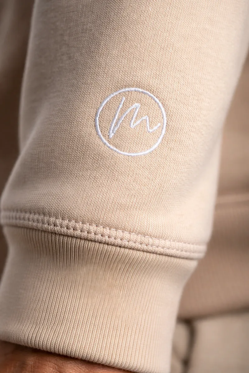 Close-up of Mainbeste embroidered monogram on hoodie sleeve