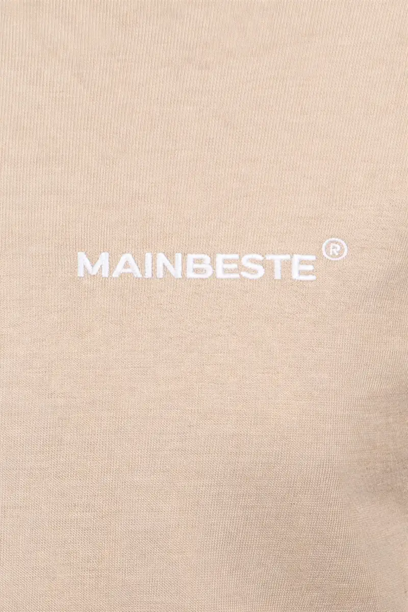 Close-up of embroidered Mainbeste logo on Sand Gold Hoodie